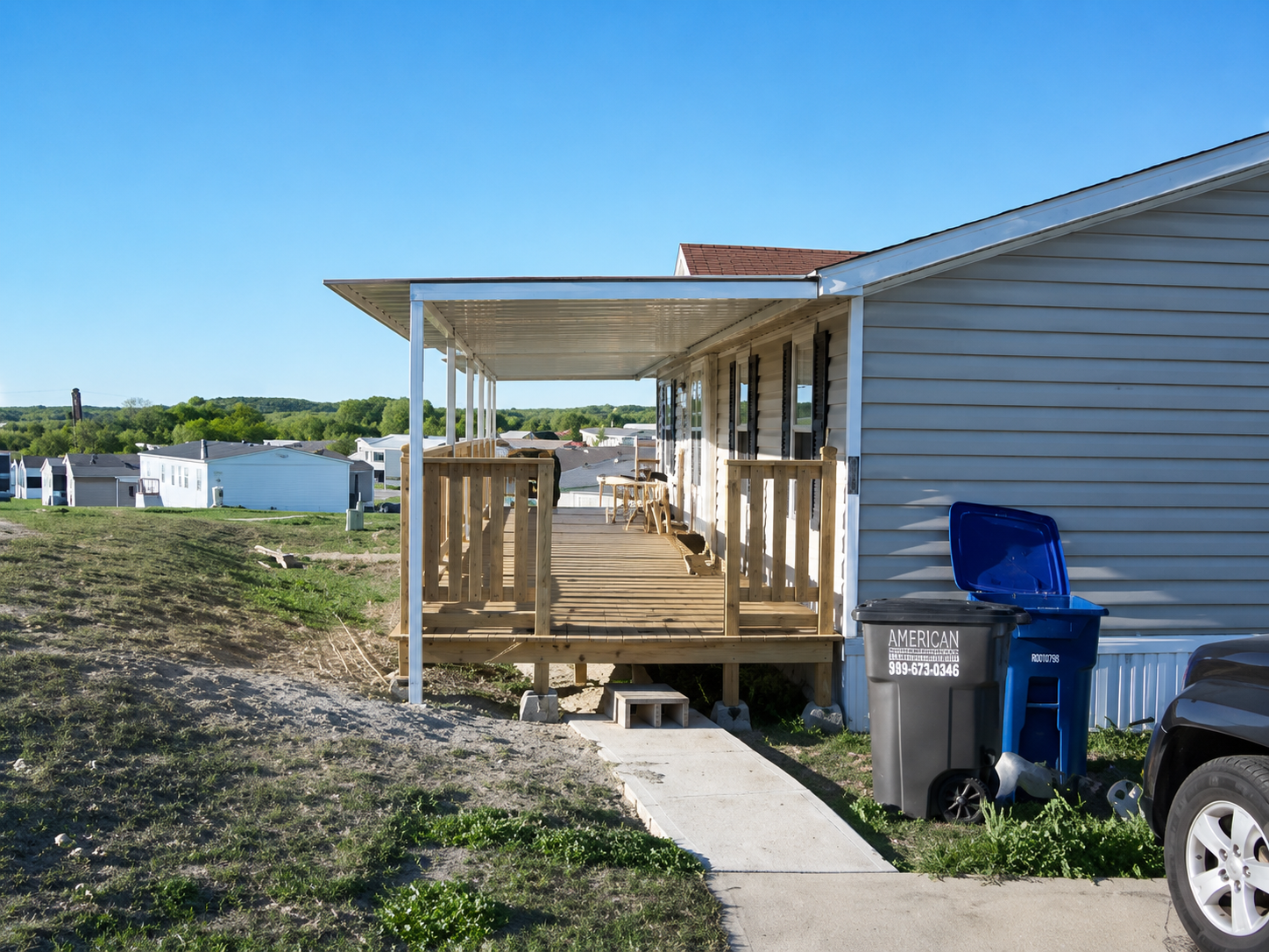 Wood deck with white metal patio cover and awning on a mobile home