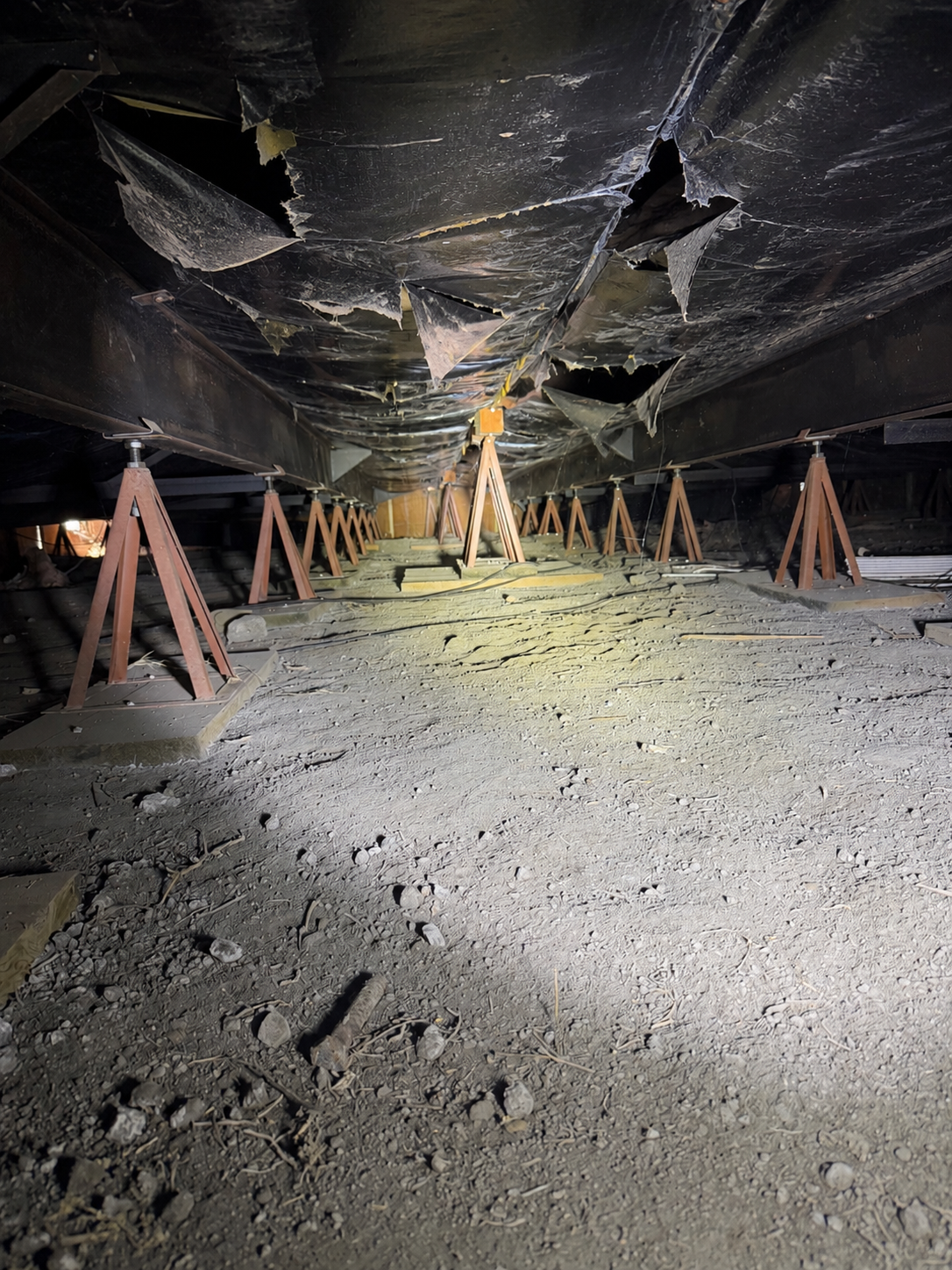 Torn vapor barrier under a mobile home allowing ground moisture to reach the subfloor
