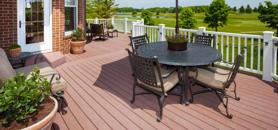 Spacious outdoor patio with metal furniture and potted plants, overlooking a lush green lawn and scenic landscape.