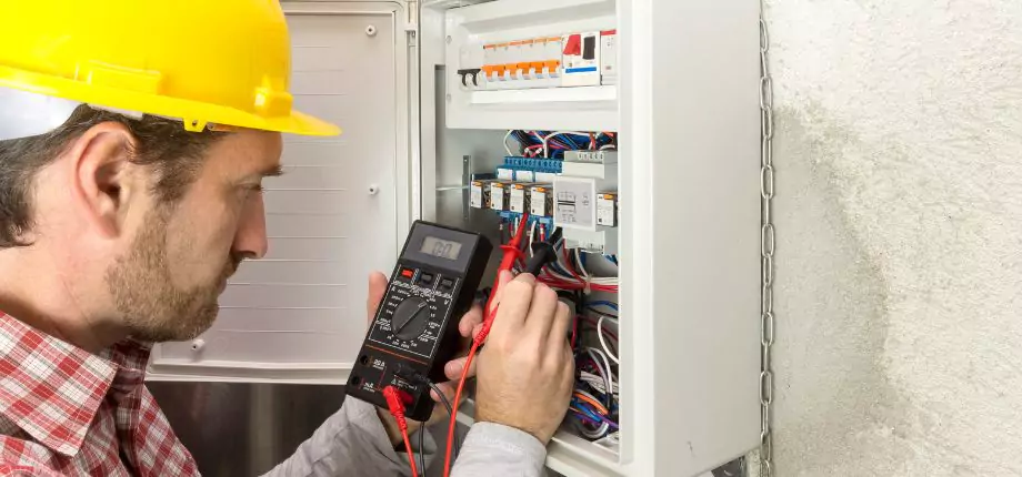 Electrician using a multimeter to test electrical wiring, emphasizing precision and safety in electrical service.