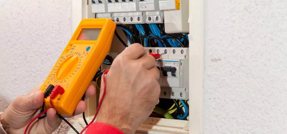 Electrician installing a light fixture on the ceiling, demonstrating electrical service skills and safety.