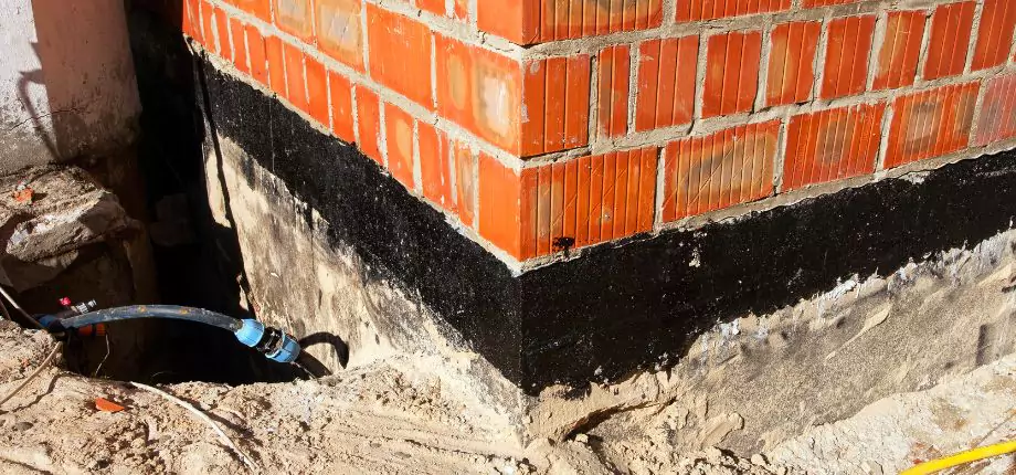 Engineer assessing a concrete foundation with measuring tools, focusing on accuracy and durability in foundation service.