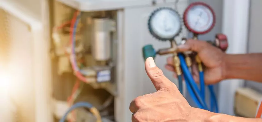 Technician adjusting HVAC gauges during an air conditioning maintenance check, ensuring optimal system performance.