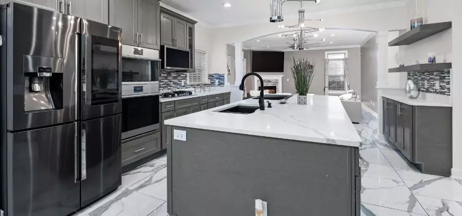 Modern kitchen with marble countertops, stainless steel appliances, and a central island sink, combining functionality with elegant design.