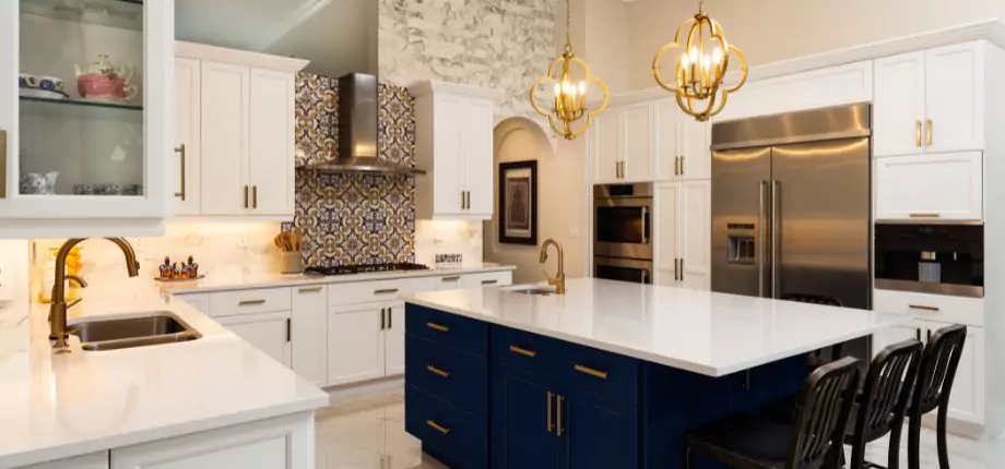 Elegant kitchen with a large white island, navy blue cabinets, gold fixtures, and decorative tile backsplash, creating a luxurious and inviting space.