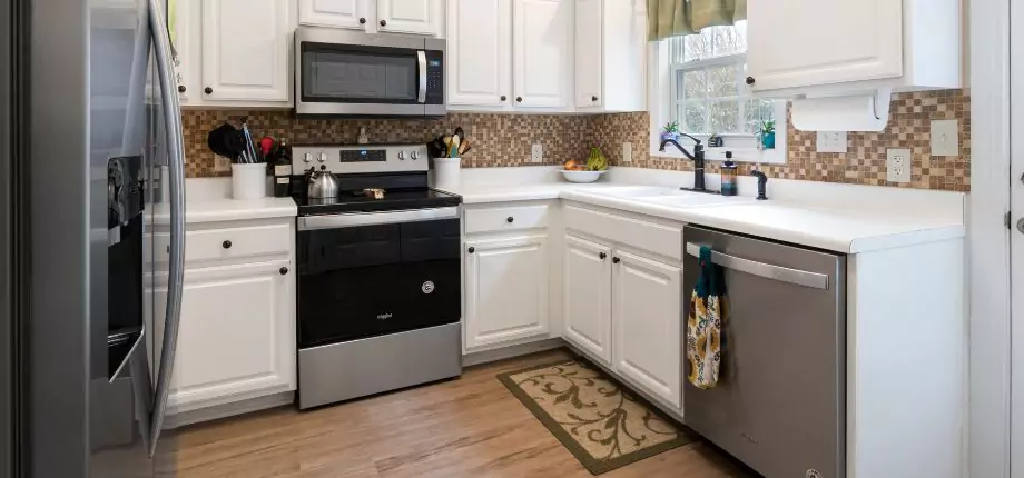 Cozy kitchen with white cabinets, stainless steel appliances, and a mosaic tile backsplash, providing a warm and functional cooking space.
