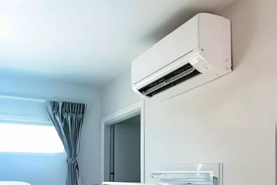 Wall-mounted air conditioning unit installed in a modern room with light-colored walls and curtains.