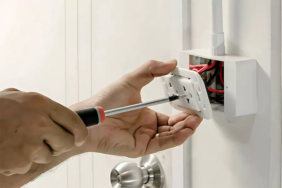Close-up of hands using a screwdriver to install or repair an electrical outlet, emphasizing precision and safety.