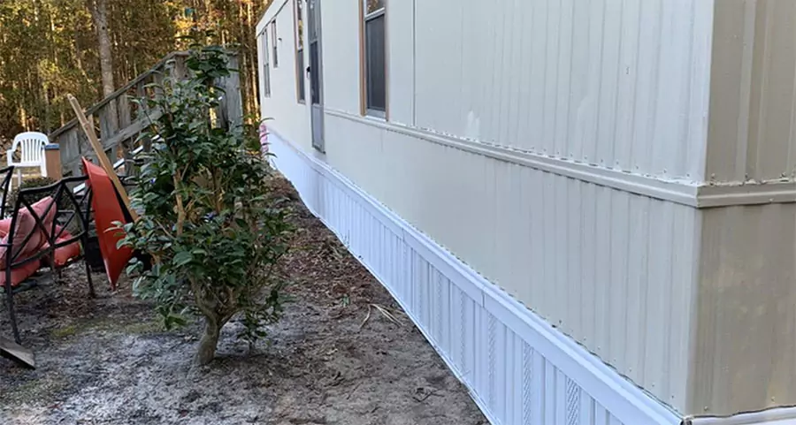 Exterior view of a mobile home with freshly installed white skirting, emphasizing quality repairs and maintenance for mobile homes.