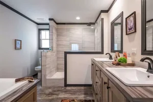 Modern mobile home bathroom remodel in Carlsbad with corner shower, double vanity sinks, framed mirrors, and updated fixtures for maximizing space.