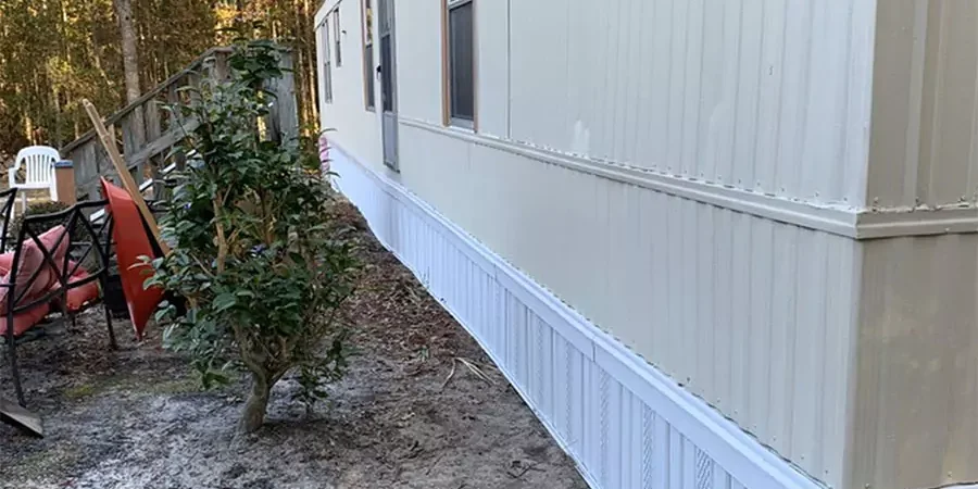 Exterior view of a mobile home with freshly installed white skirting, emphasizing quality repairs and maintenance for mobile homes.