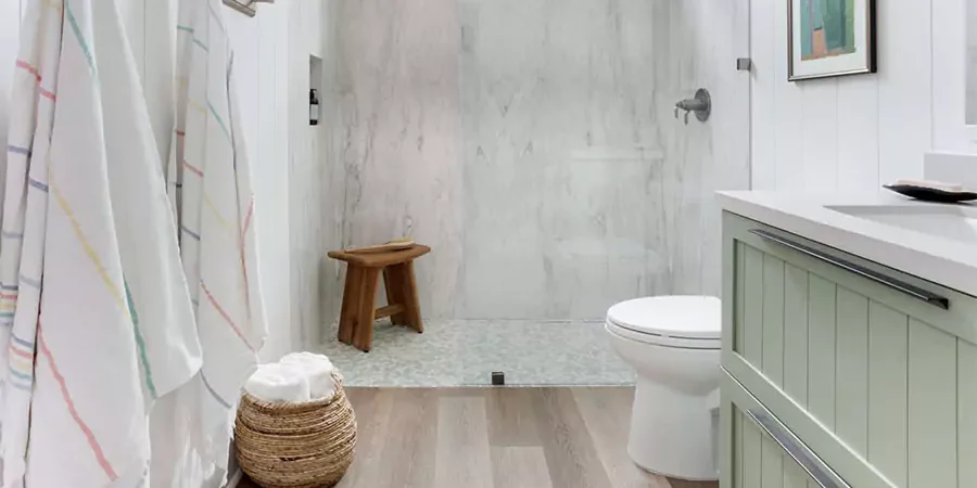 Modern small bathroom remodel with glass shower, light wood flooring, mint green vanity, and woven storage basket — stylish design idea for mobile homes in Huntington Beach, California.