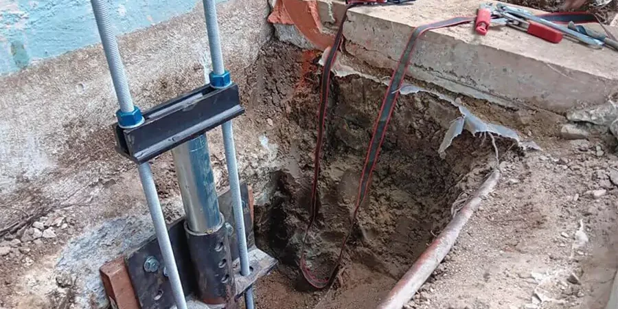 Foundation repair process for slab foundation using helical piers in Carlsbad, demonstrating an effective concrete leveling method for foundation stabilization.